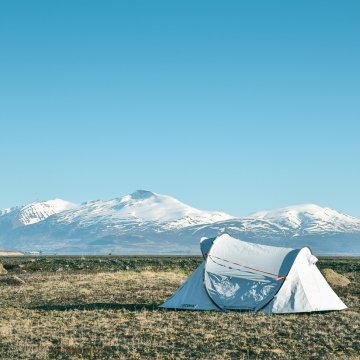 tent setup outside on an open field with mountains in the backdrop